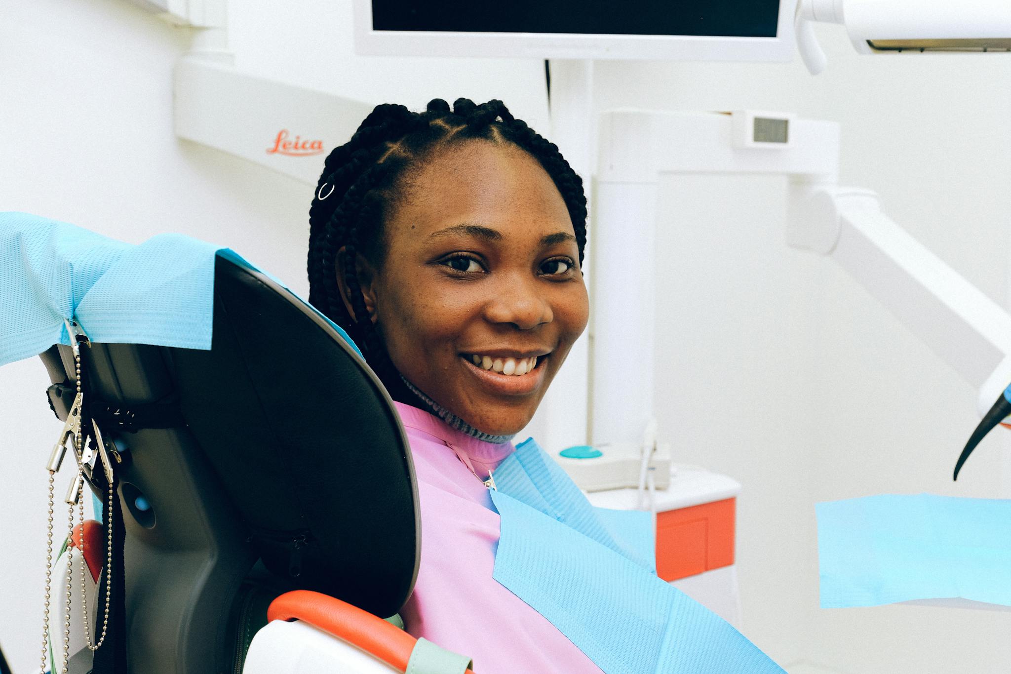 African American woman smiling while sitting in a dental clinic chair during a check-up.