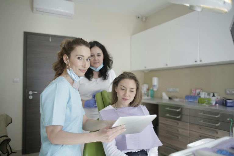 Dentists and patient engaging over a tablet in a clean, modern dental clinic.