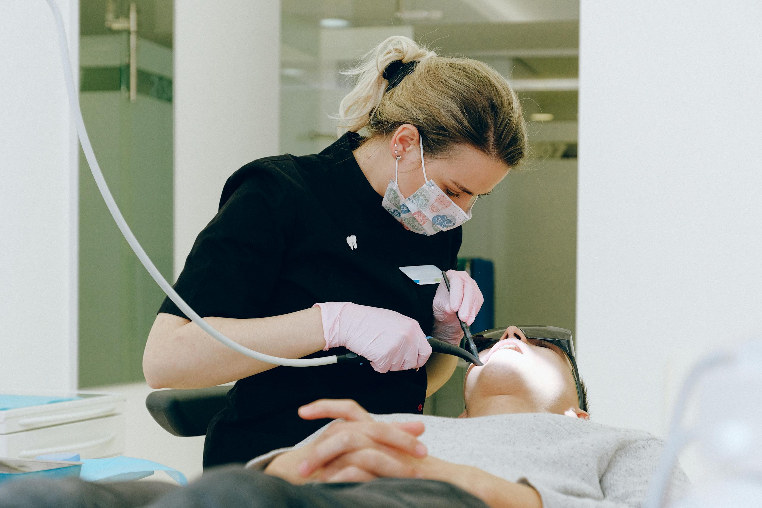 Female dentist performs a dental procedure on a patient in a clean, modern clinic setting.